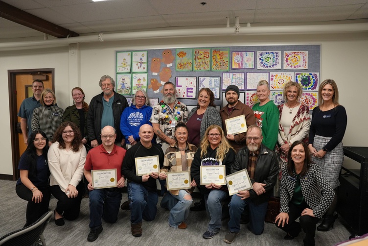 A group of people pose for a photo, holding certificates of recognition from the Oak Harbor Public Schools.