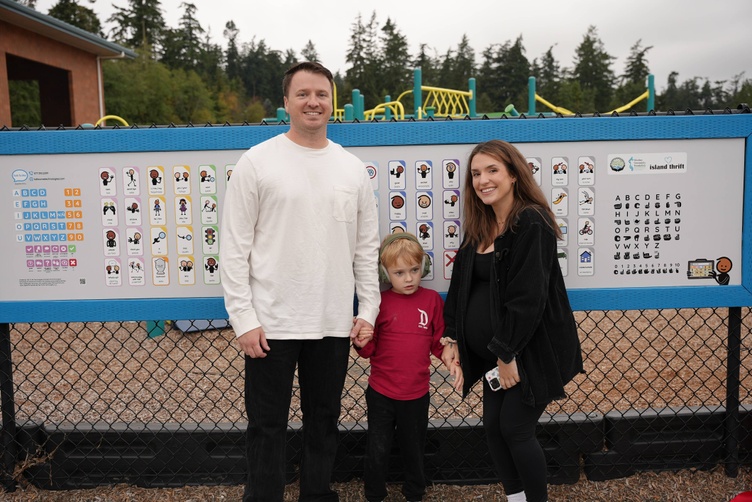 parents and son standing in front of communication board