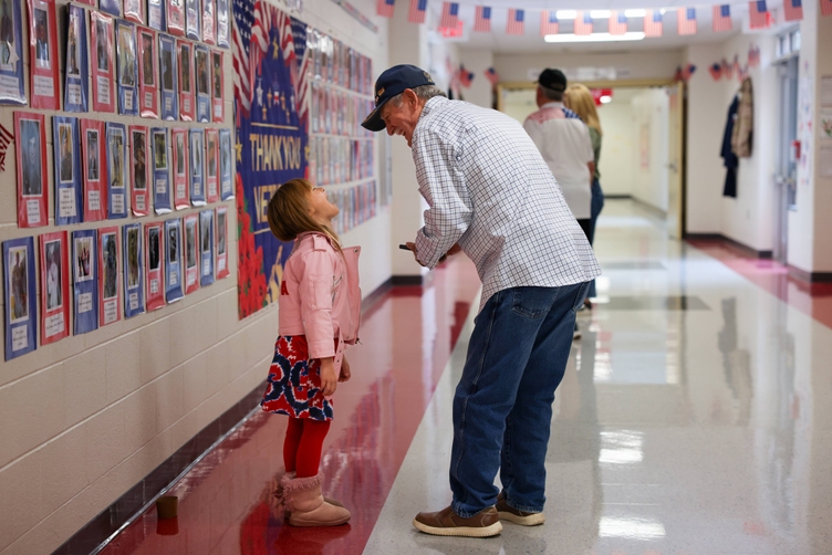 A veteran laughs with a student in the hall at A.T. Allen Elementary School.