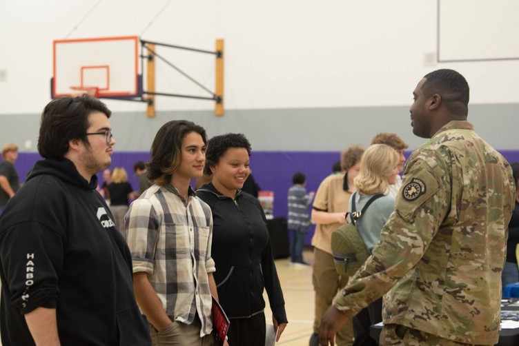 students speak with military personnel