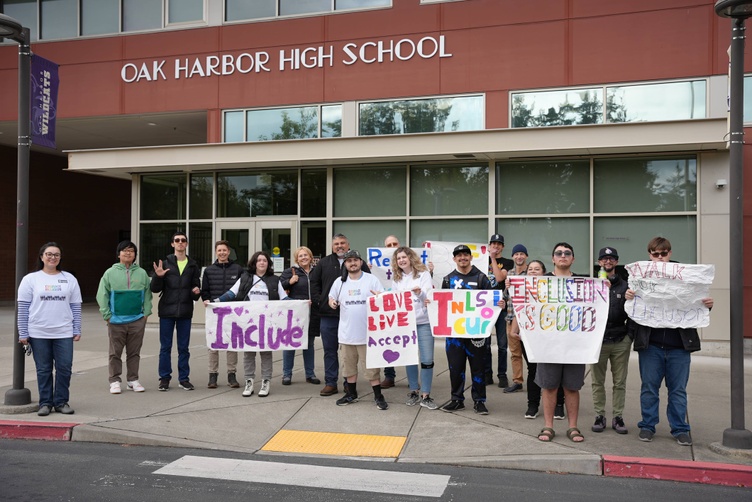 families stand in front of high school with signs