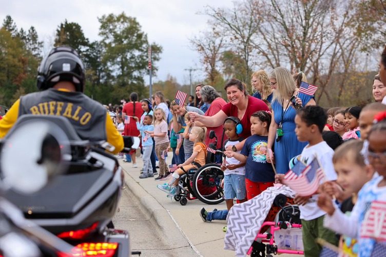 A veteran drives by a group of students as part of the Veterans Day motorcycle parade at W.M. Irvin Elementary School.