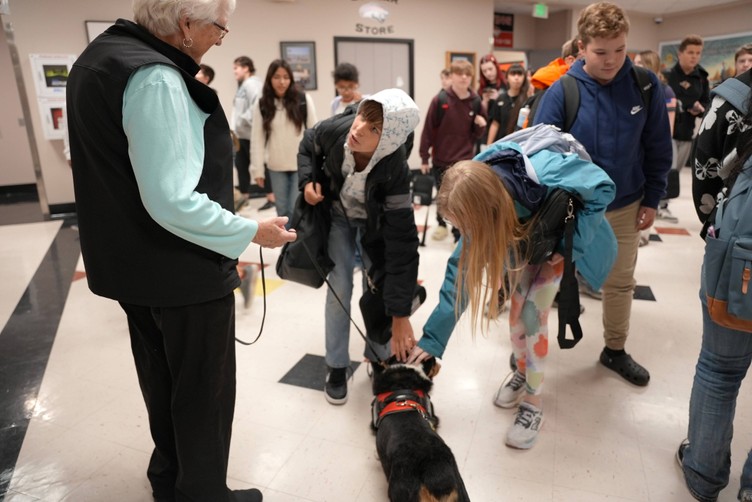 students pet a therapy dog in the hallway