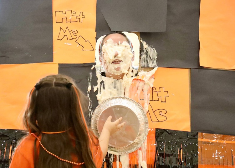 A staff member prepares to receive a pie to the face