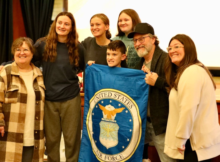 A veteran poses with students after the ceremony