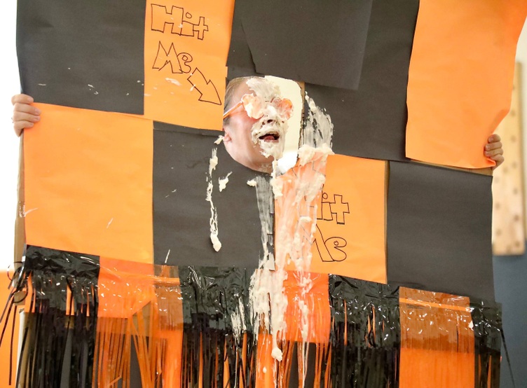 A staff member receives a pie to the face