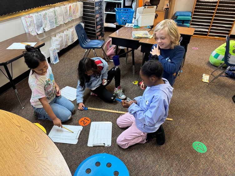 elementary students using spring scale with cars