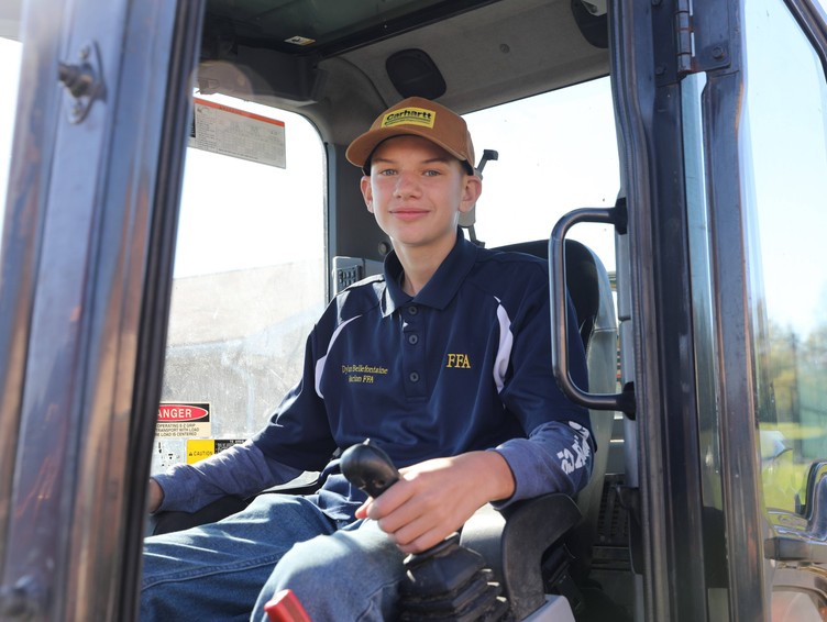 A student sits in the cab of an excavator