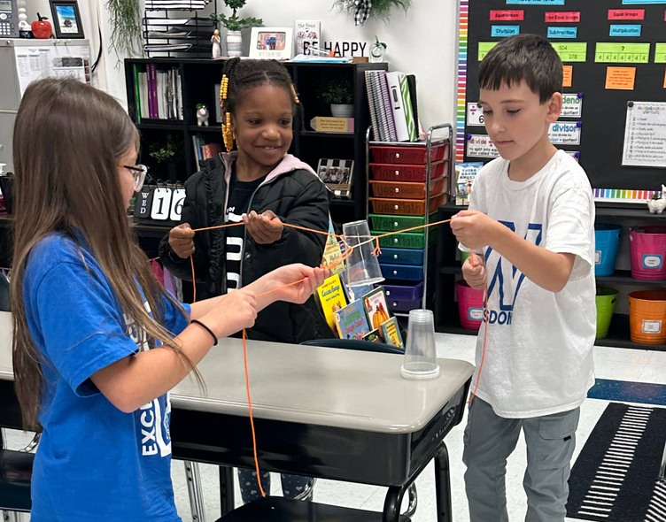 3 people around desk with strings and paper