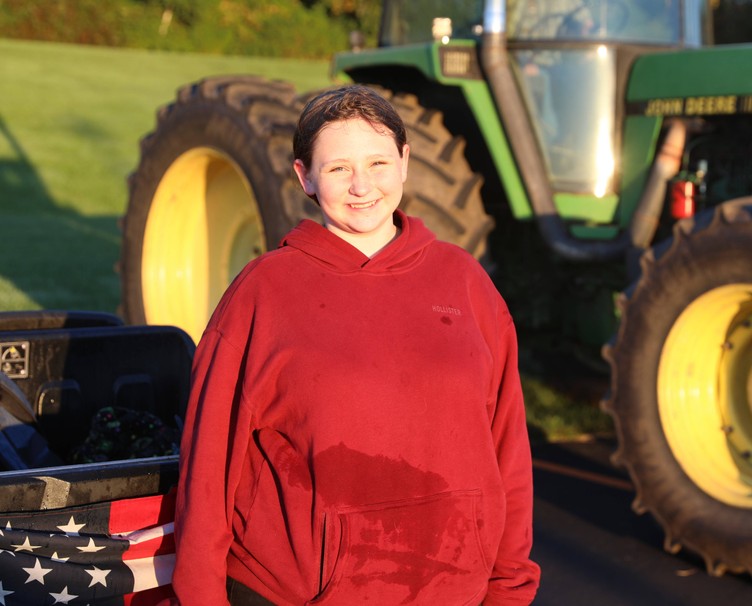 A student smiles while standing behind a four-wheeler