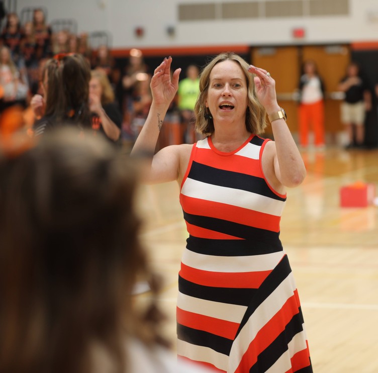 A teacher directs the choir as it sings the national anthem