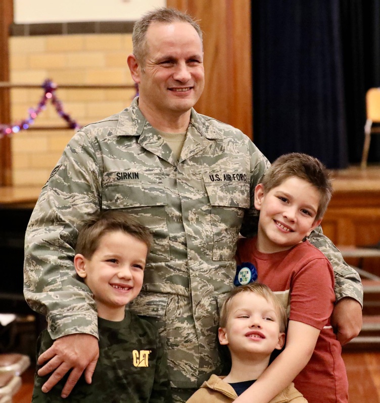 A veteran poses with students after the ceremony