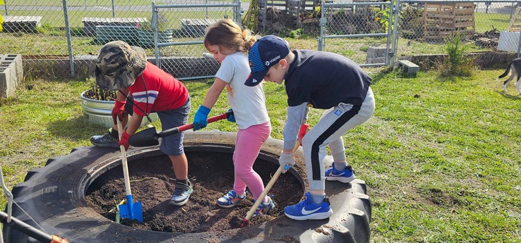 children gardening with small shovels in a used tire planter