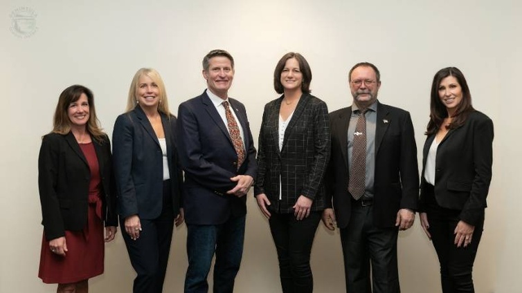 A group photo of the PSD Board of Directors and Supt. Bahr with a beige background. The board members are dressed in their business attire. From left to right: Director Lori Glover, Supt. Krestin Bahr, Director David Olson, Director Jennifer Butler, Director Chuck West, Director Natalie Wimberley