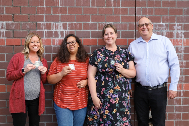  A group of four people stand in front of a brick wall and smile 