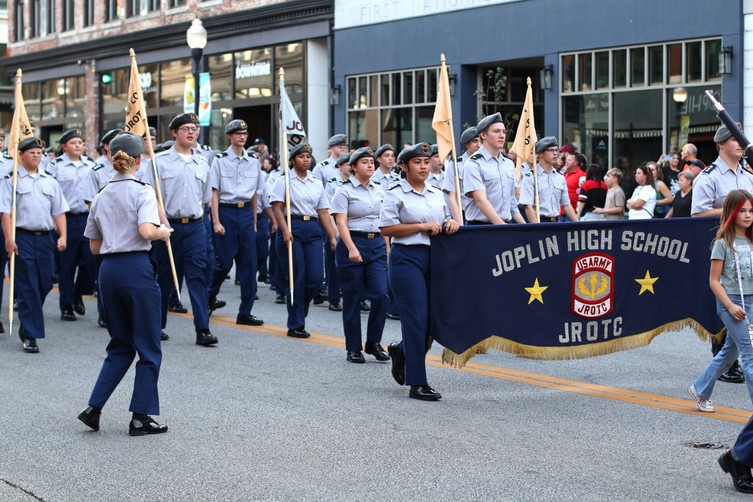 Members of the JHS JROTC march in the parade, wearing matching uniforms and bearing an official parade banner at their front.