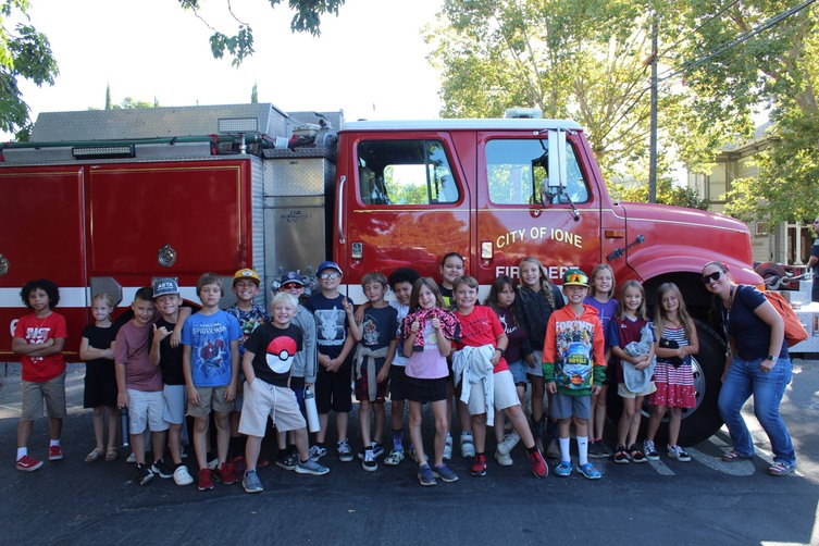 A group of elementary students pose in front of a fire truck