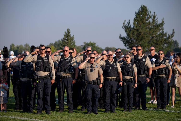 Policy and law enforcement stand saluting flag