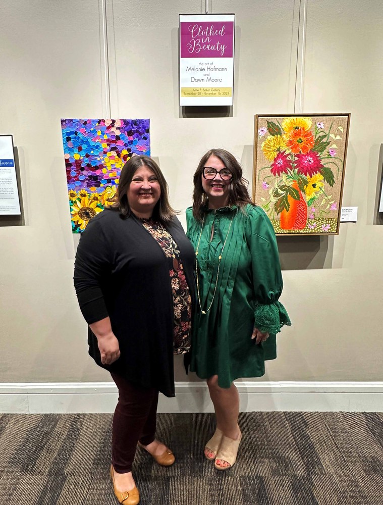 2 people stand in front of two paintings