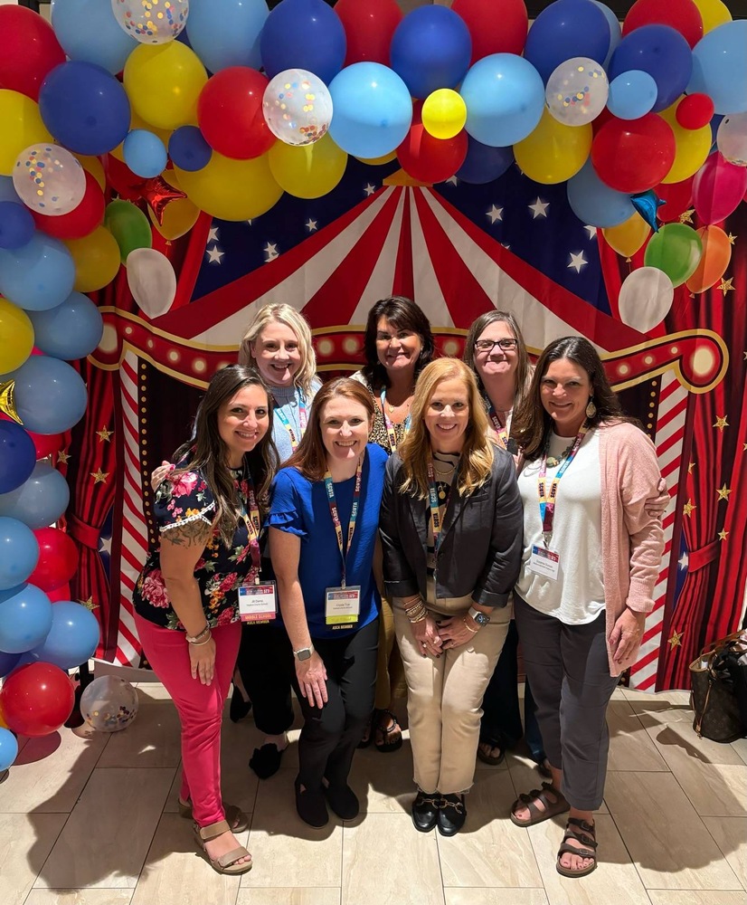 7 people pose in front of circus backdrop