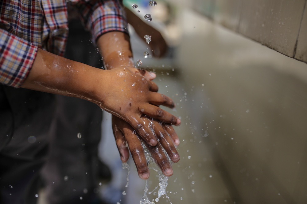 Bild på ett barns händer under en kran med rinnande vatten.