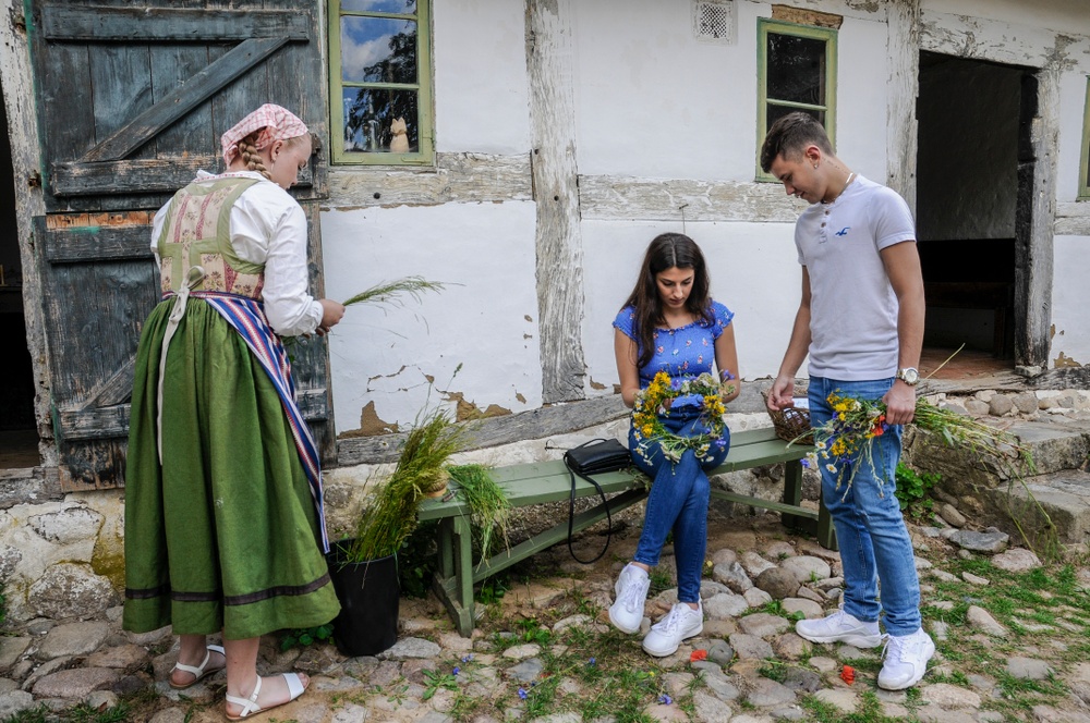 Besökare binder kransar på Gamlegårds innergård, tillsammans med en av Östarps värdar. Foto: Viveca Ohlsson, Kulturen