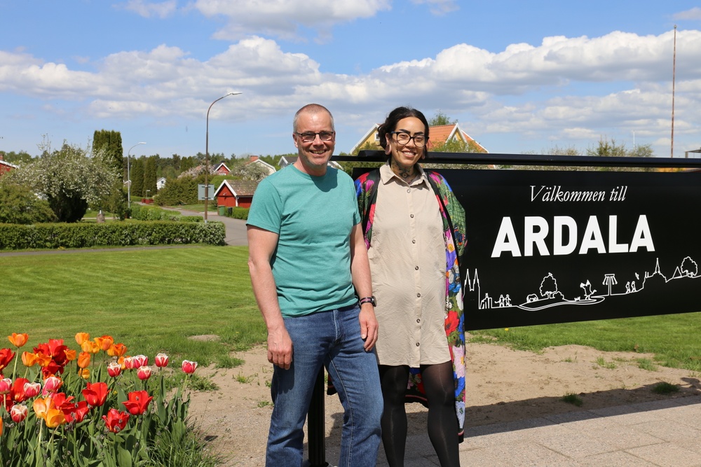 En man och en kvinna står vidArdalas välkomsskylt