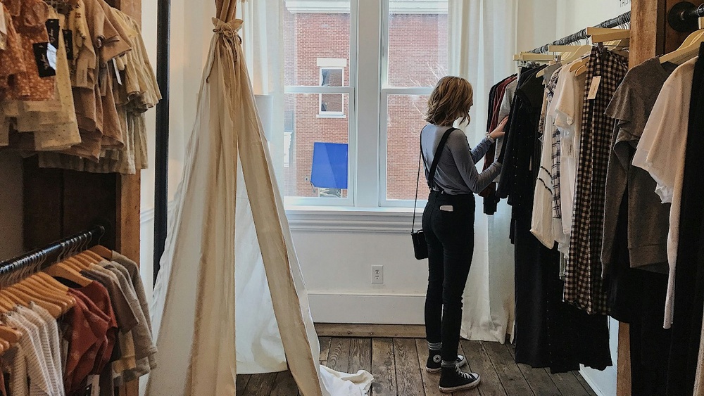 En kvinna tittar på kläder i en klädbutik. 