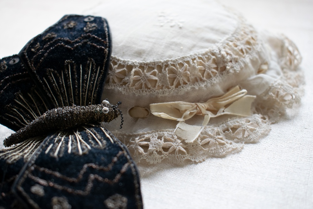 Textila accessoarer; en svart fjäril och en vit hätta med rosett.
