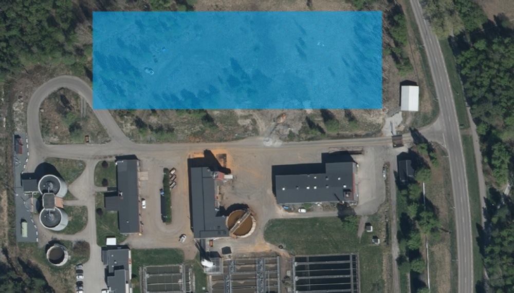 Ett flygfoto över Främby avloppsreningsverk som även visar var den nya anläggningen ska placeras. Ytan är markerad med ett blått raster.