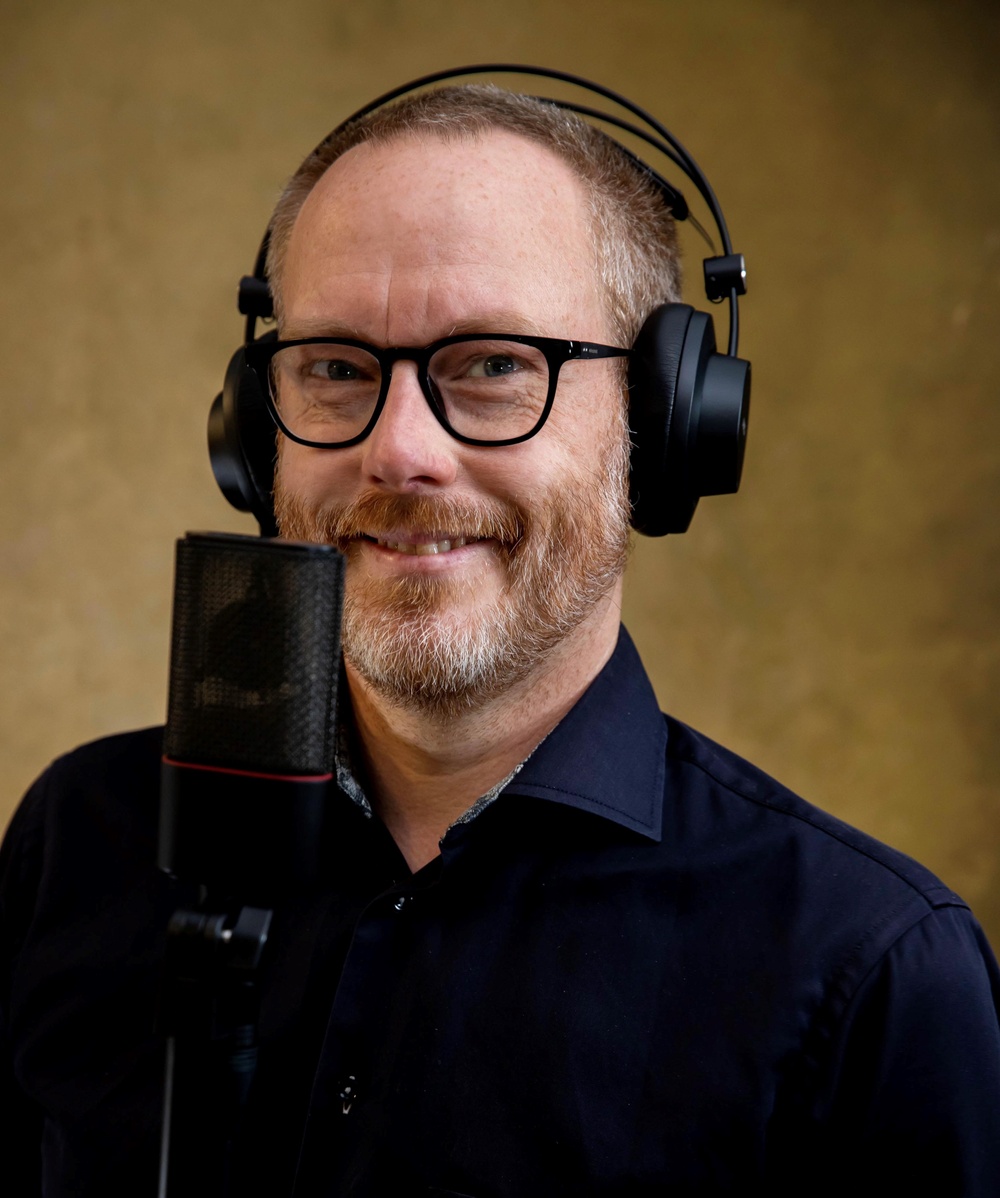Mats Börjesson står med hörlurar framför en mikrofon.