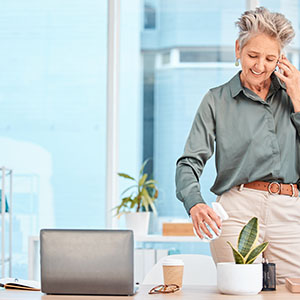 office lady in phone watering the plant