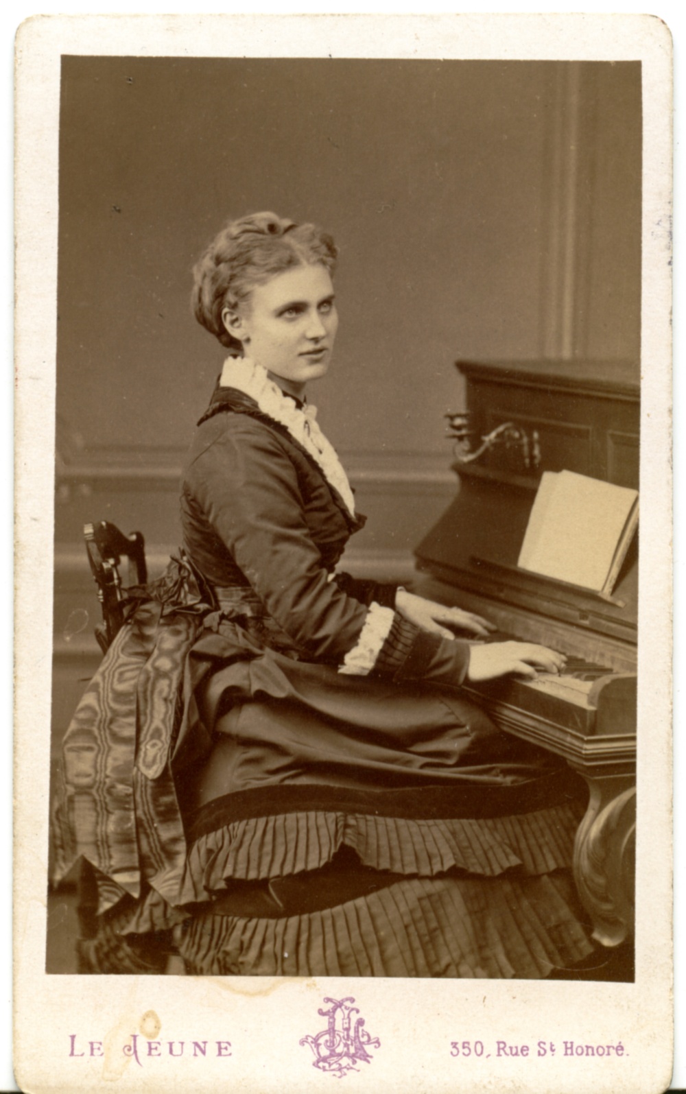 Fotografi av operasångerskan Kristina Nilsson i halvprofil sittande vid piano.