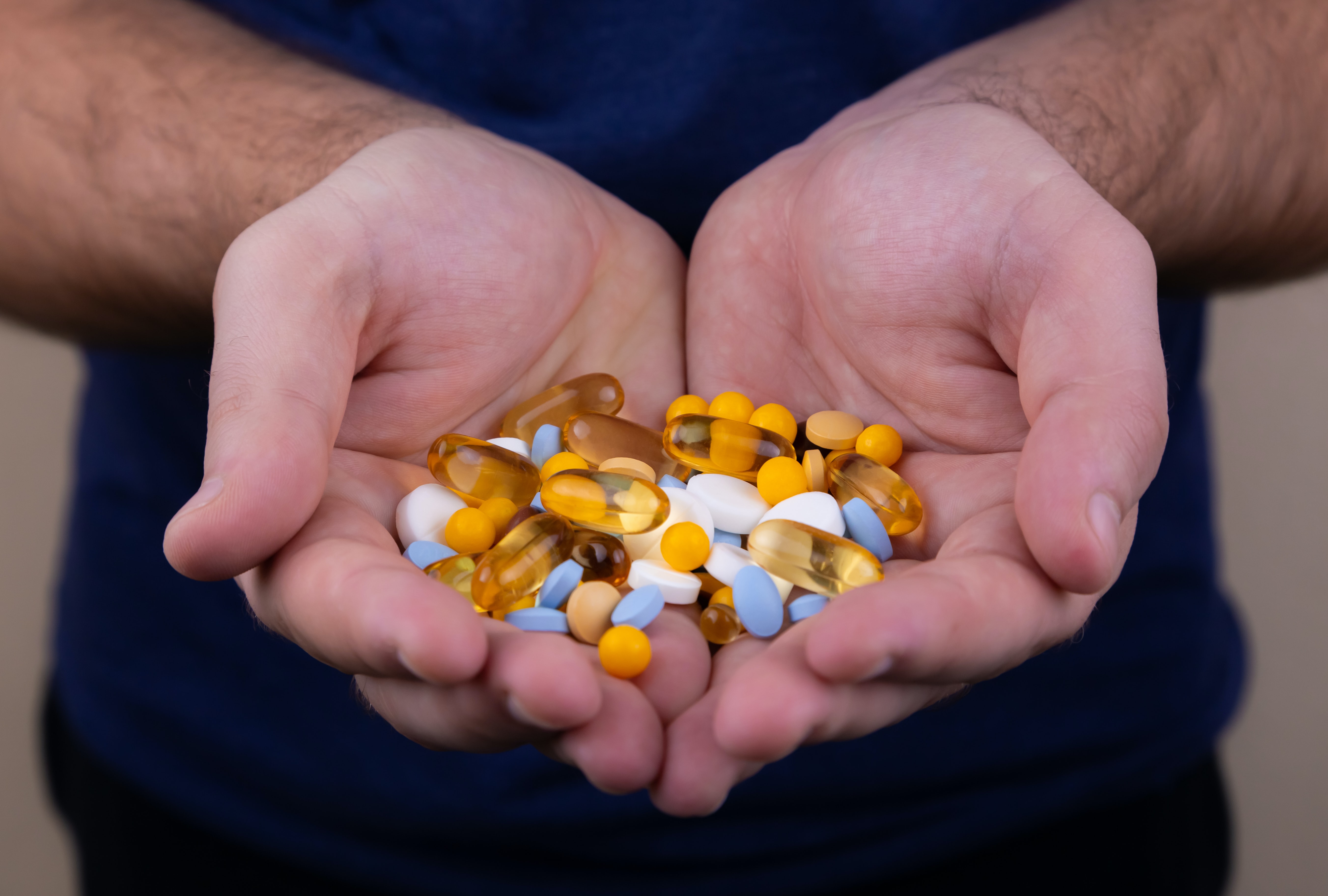 Are SARMs in pill form legal? Image of a man holding 30 assorted pills.