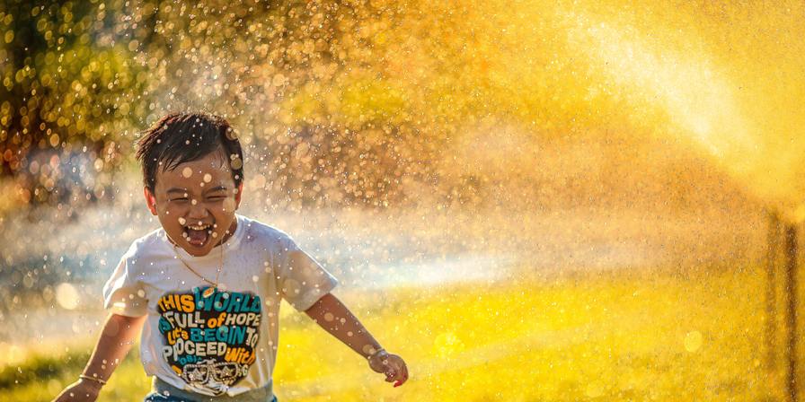 A child running through a sprinkler