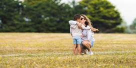 An adult and a child hugging in a field