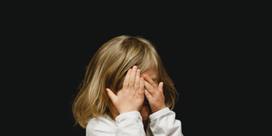 A child covering their face with their hands