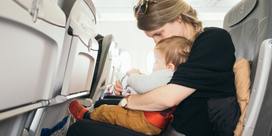 A woman sitting on a plane with a child on her lap