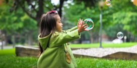A young girl playing with bubbles 