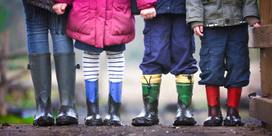 Three children and an adult standing in rainboots