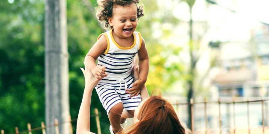 A woman lifting up a smiling toddler