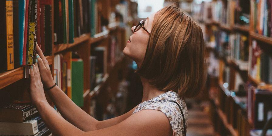 Woman with her hands on a bookshelf in a library