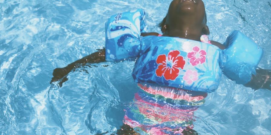 A child with floaties swimming in a pool