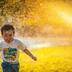 A child running through a sprinkler