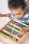 Young boy shifting beads on a wooden abacus counting toy
