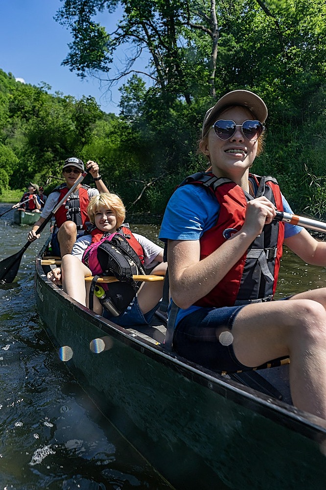 3 people are in a canoe wearing PFDs.