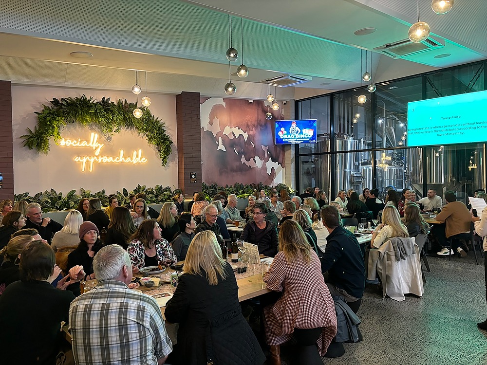 Group of people sitting down eating, playing pub quiz