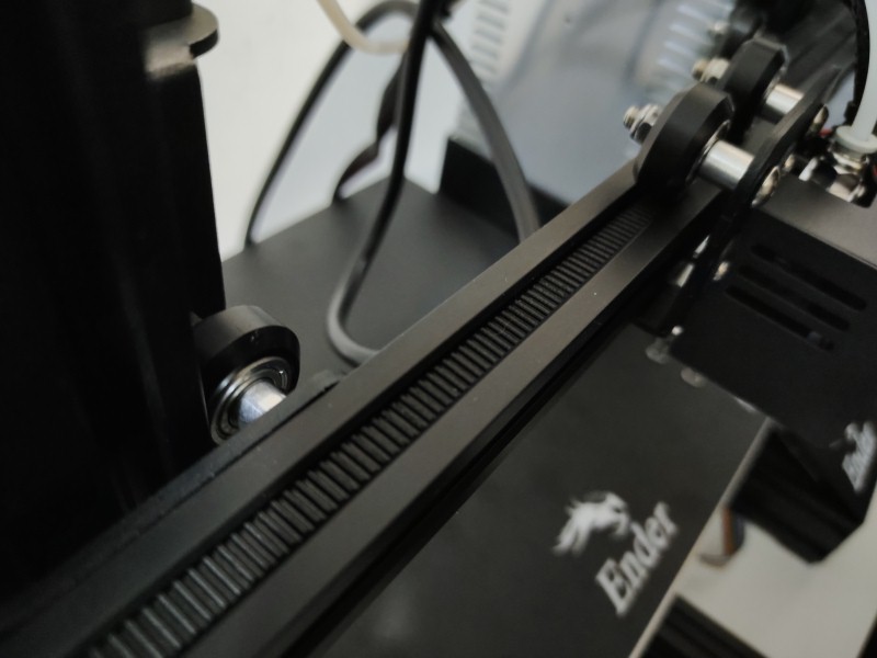 This image shows a close-up of a 3D printer's timing belt and pulley, key components needing proper alignment for optimal printer function.