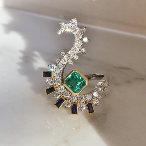 A close-up of a Nature Inspired Emerald Stone Ring placed on a shiny surface.