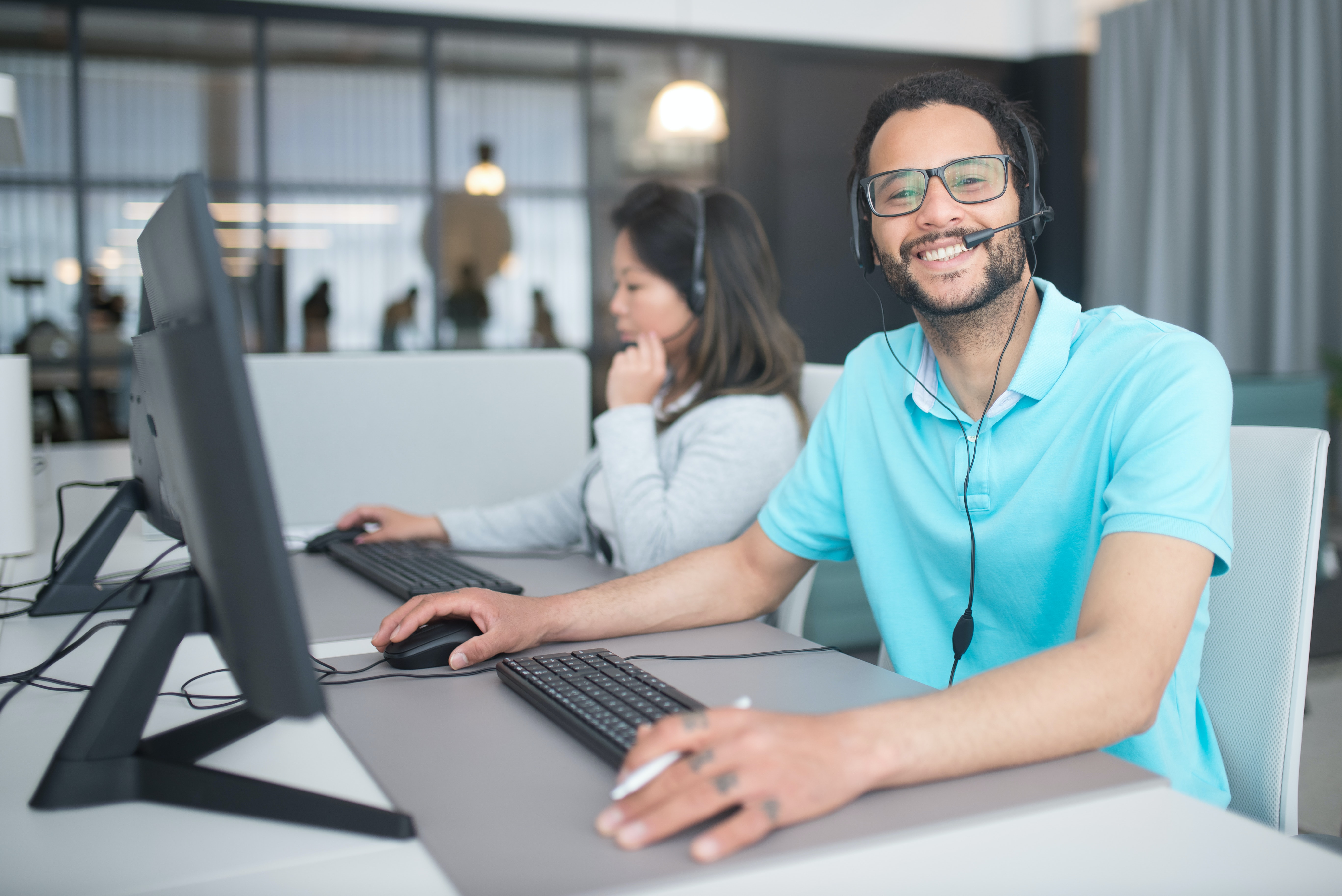 a smiling man and a woman working in a call center